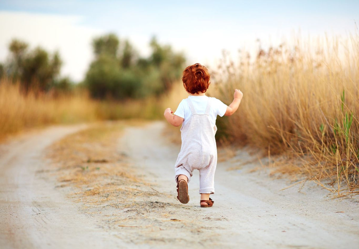Toddler boy running outside.