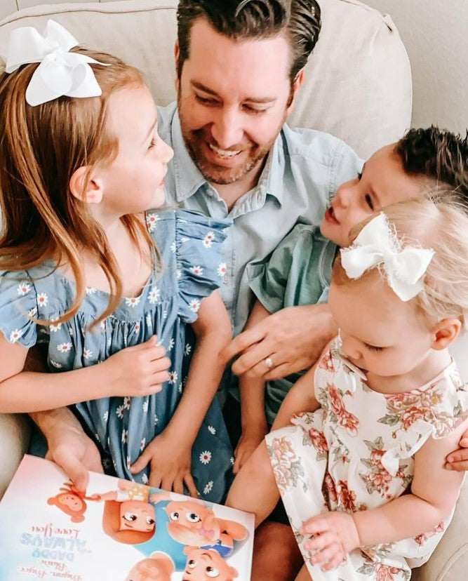 A father sits with his three children as they read a Hooray Heroes personalized book. the best Father's Day gift.