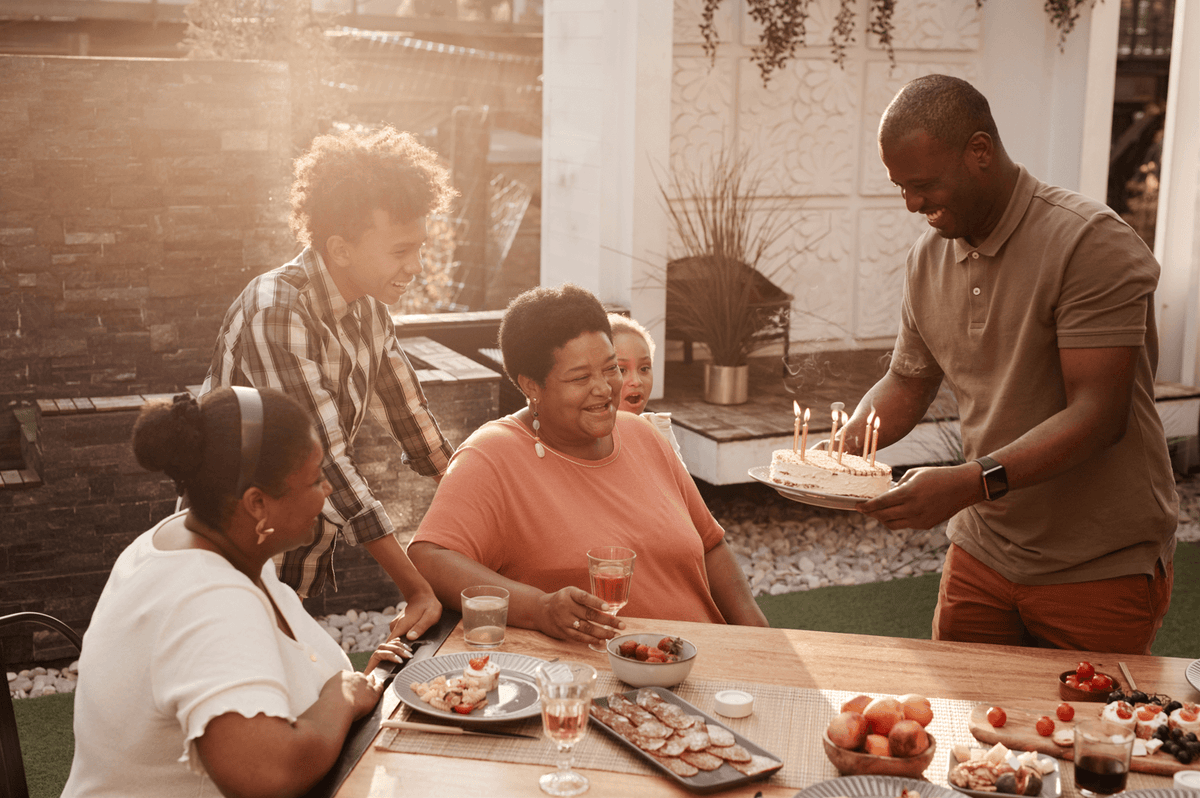 A grandmother, surrounded by her children and grandchildren, getting a birthday cake on her birthday.