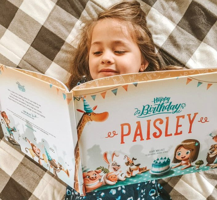 A little girl reading a personalized birthday book from Hooray Heroes.
