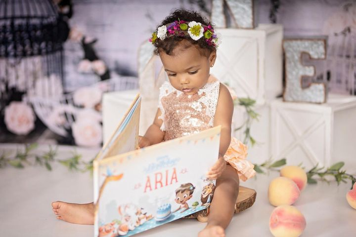 A little girl holding the personalized birthday book by Hooray Heroes.