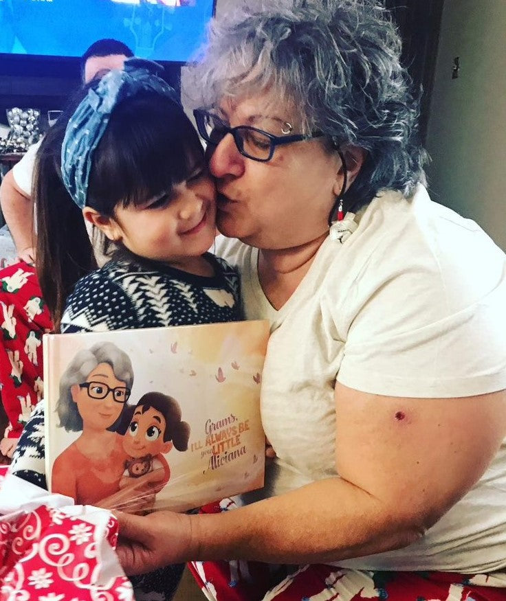 A grandmother kisses her granddaughter who has given her a personalized book for Christmas.