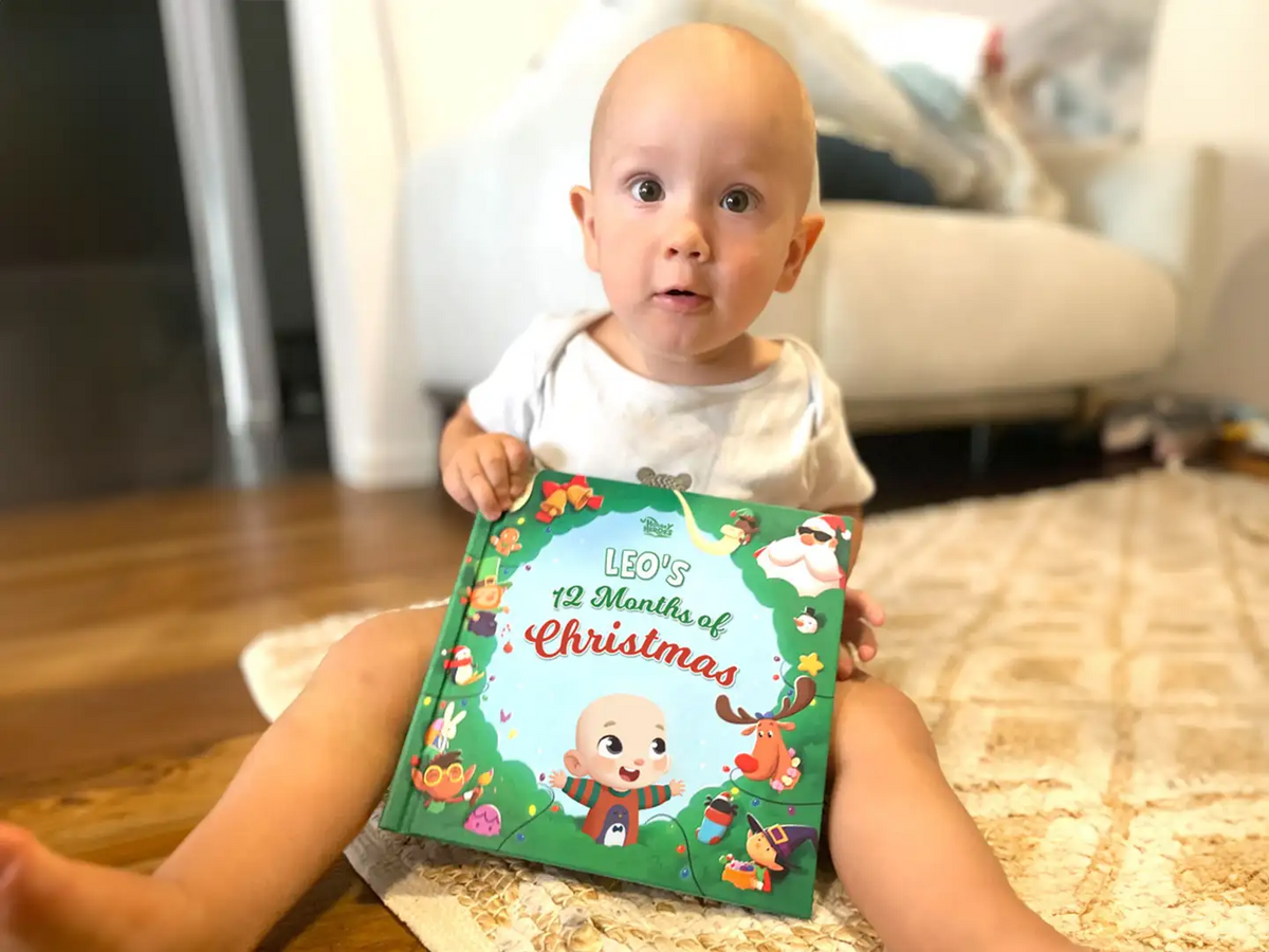 Little boy holding his new personalized book for Christmas with his character on the cover.