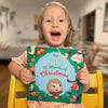 Little girl is holding her Christmas present - a festive personalized book.
