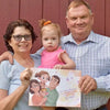 Grandparents and a little girl holding a book from Hooray Heroes dedicated to grandparents.