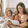 Mother and her two kids are reading a custom storybook in bed.