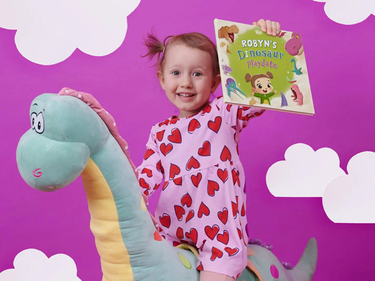 Little dinosaur lover Robyn is holding her new, awesome personalized book about herself and dinos.
