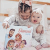 Two girls smiling while looking at personalized illustrations made just for their family.