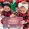 Two little girls with head bows are holding the personalized book for siblings they received as a Christmas present