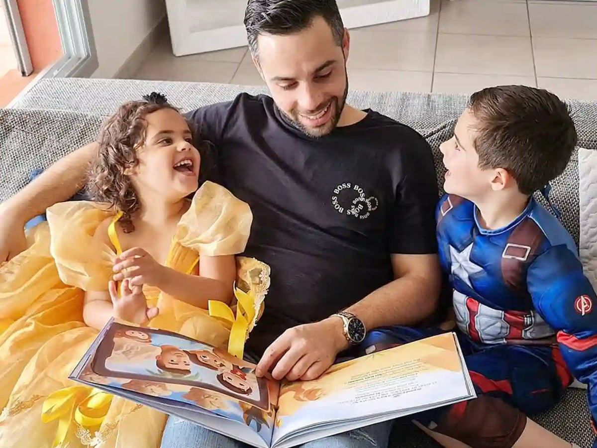Kids are laughing at father who is reading their personalized book for Father's day.