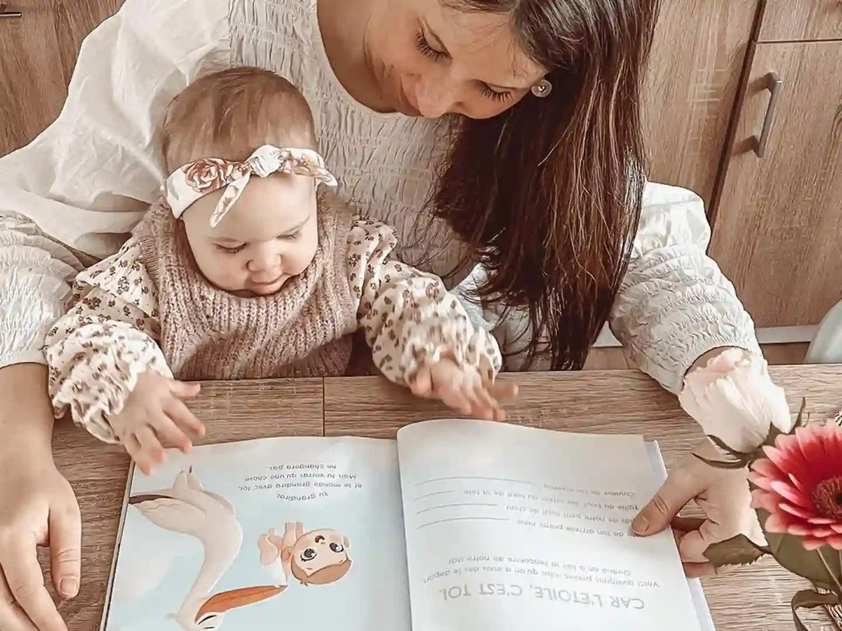 Little girl is looking at the customized book she got when she was born.