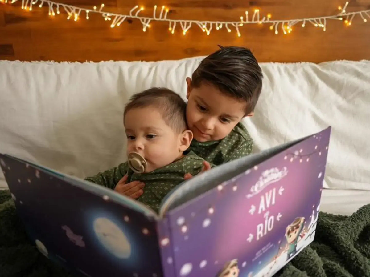 Two boys are sitting on the bed, reading from their custom Christmas storybook made just for them.