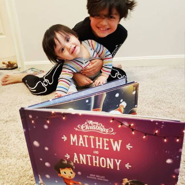 Two brothers smile at their customised Christmas book all about the two of them and their festive adventures.