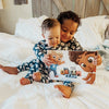 Kids sitting on a bed holding their personalized adventure book for two. 