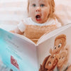 A girl looking at a personalized book for parents and their child.