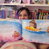 A seven-year-old girl is holding her personalized birthday book.