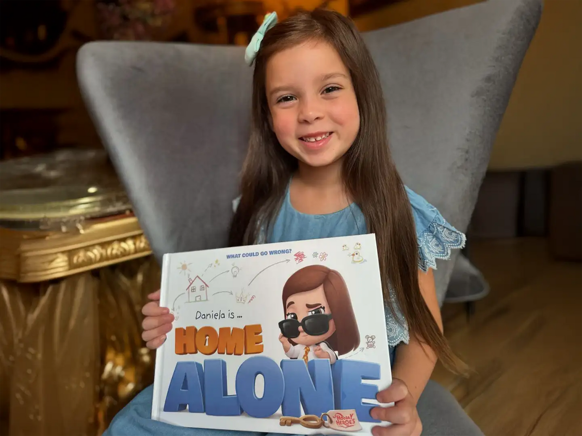 A girl is holding her personalized home alone book.