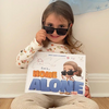 A smiling girl is posing with her new personalized Home Alone book from Hooray Heroes.