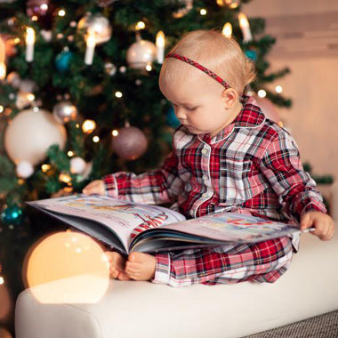 A toddler admires the illustrations in her unique, DIY Christmas book, a beautiful gift for kids.