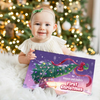 Baby holding a personalized Christmas gift book titled “Rowan and Dada’s First Christmas 2025.”