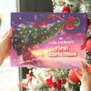 Hands holding a personalized Christmas book titled “Leslie and Mama’s First Christmas 2025” next to a decorated tree.