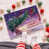 Personalized Christmas book titled “Lucas and Mom’s First Christmas 2025” lying next to baby’s feet and festive decorations.