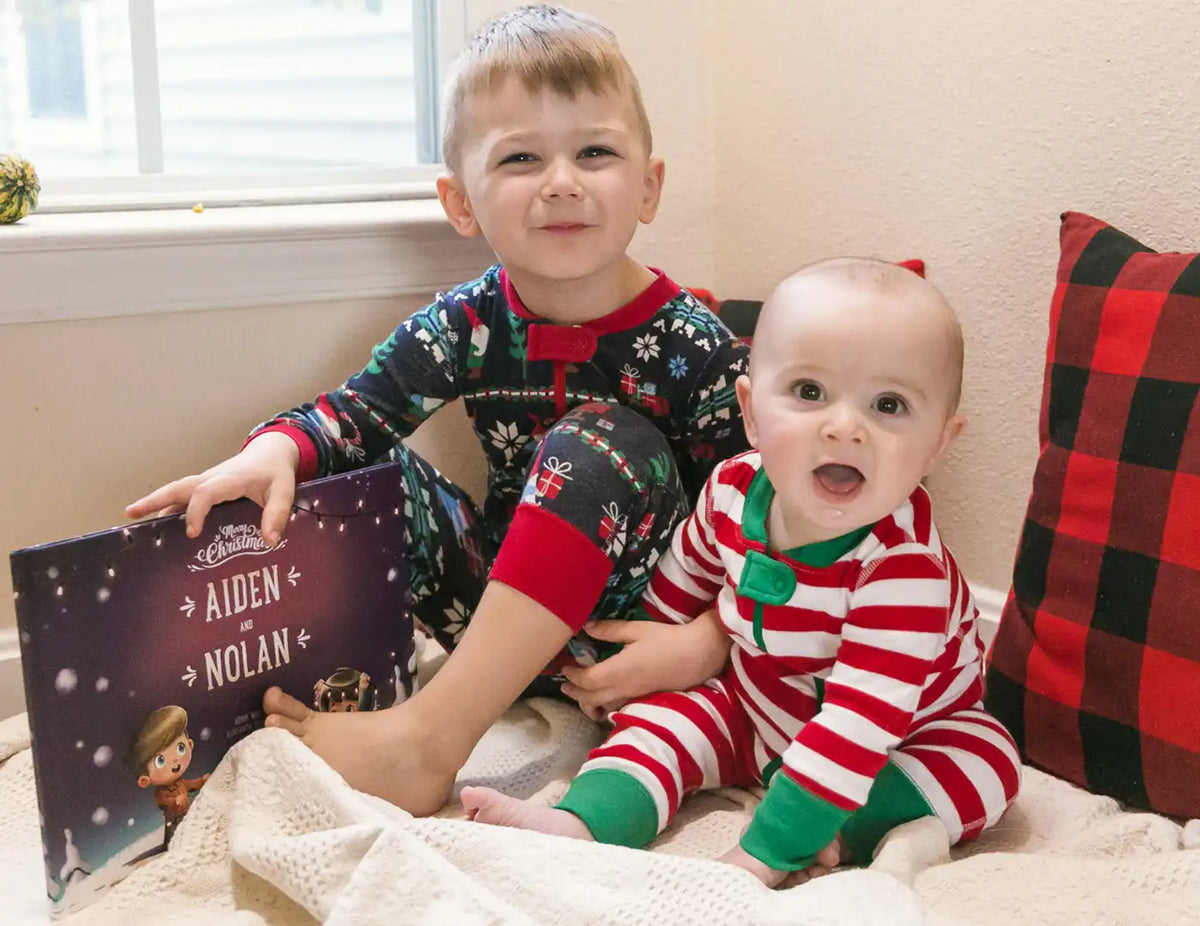 Cute little brothers dressed in Christmas pyjamas are happy about their personalized Christmas book just about them.