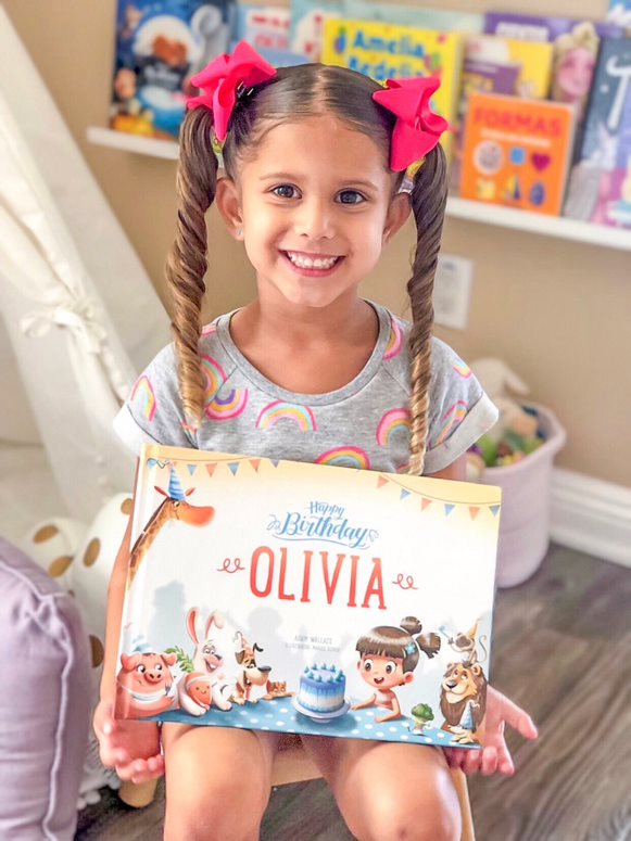 A little girl holding a book called Happy Birthday Olivia. Happy Birthday Jesse. Hooray Heroes personalized children's book - a perfect birthday present for kids.