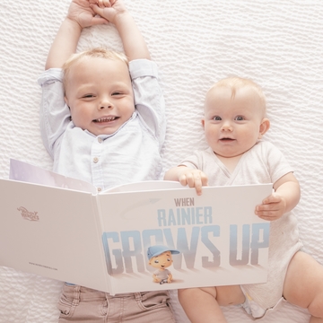 Two kids with a beautiful custom book for father and child about what the child may grow up to be.