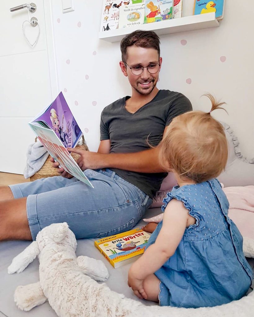 A happy man with his child and a personalized book for daddies.