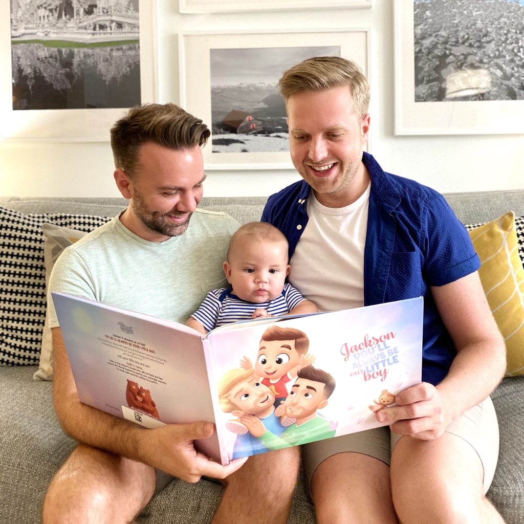 A happy couple and a child reading the Hooray Heroes personalized book for same-sex couples.