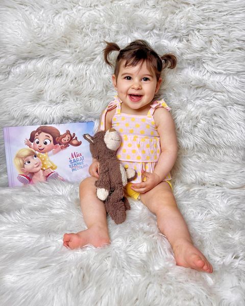 A little girl with a toy and her own custom book for her and her mommy.