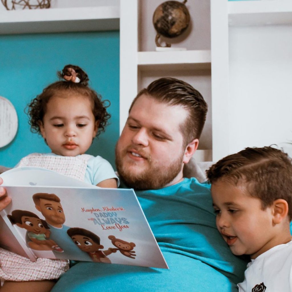 A family of 3 reading a personalized book for daddies.