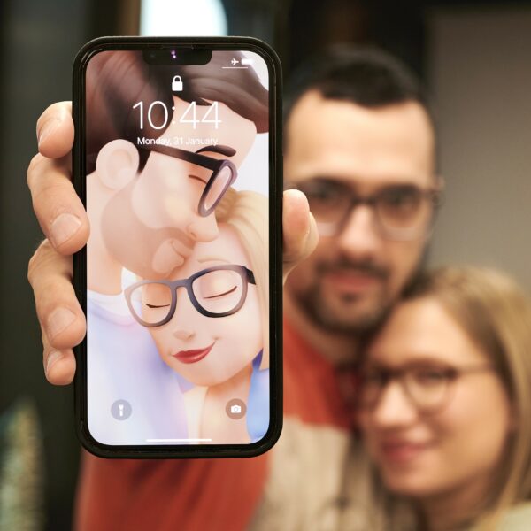 A couple holding a mobile phone with a personalized wallpaper for couples by Hooray Heroes.