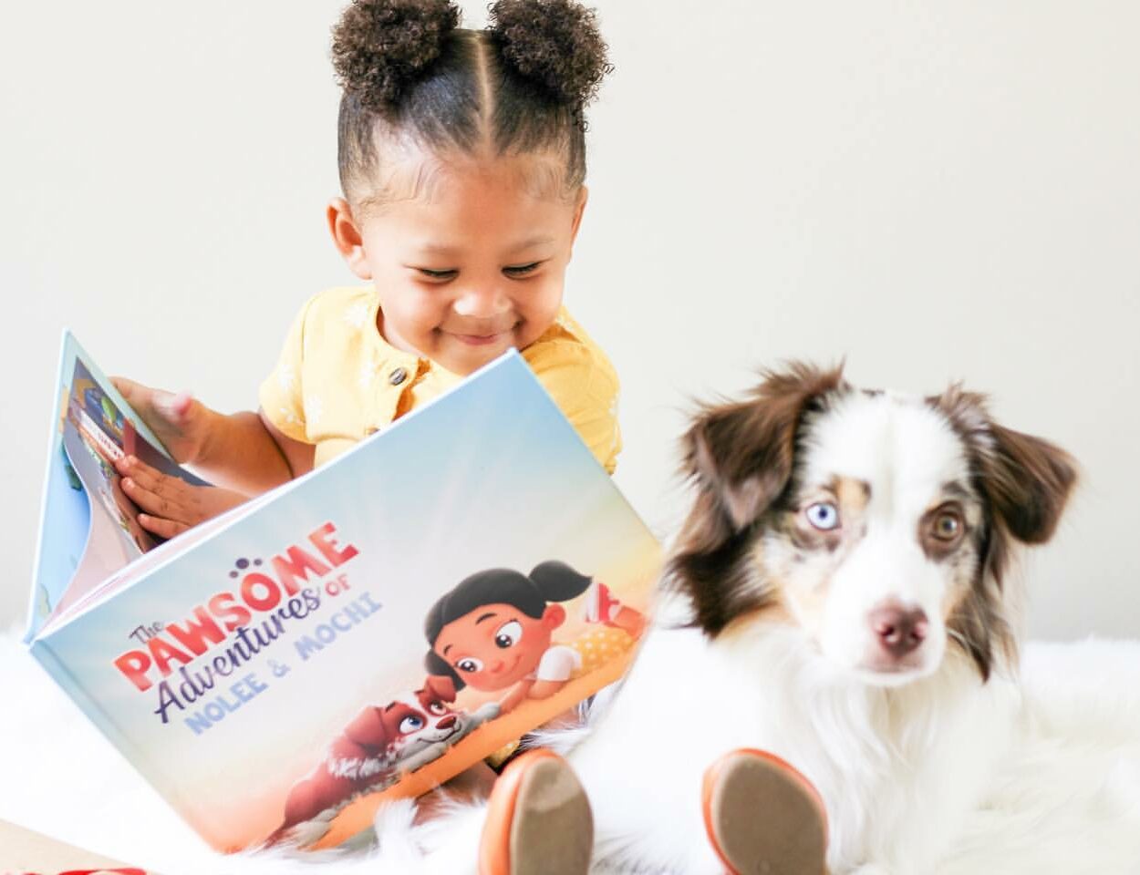 A little girl reads a personalized pets book to her dog.