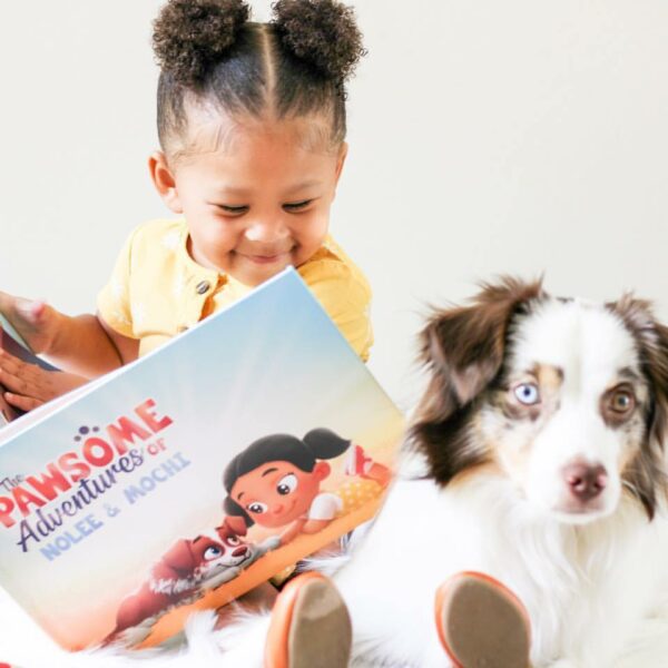 A little girl reads a personalized pets book to her dog.