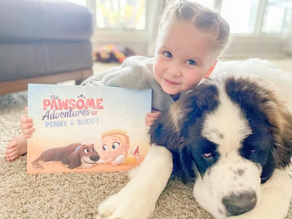 A little girl snuggles her dog while holding a personalized book about her and her furry friend.