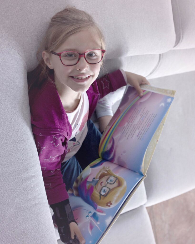 A little girl reading a personalized Hooray Heroes Birthday Book and smiling.