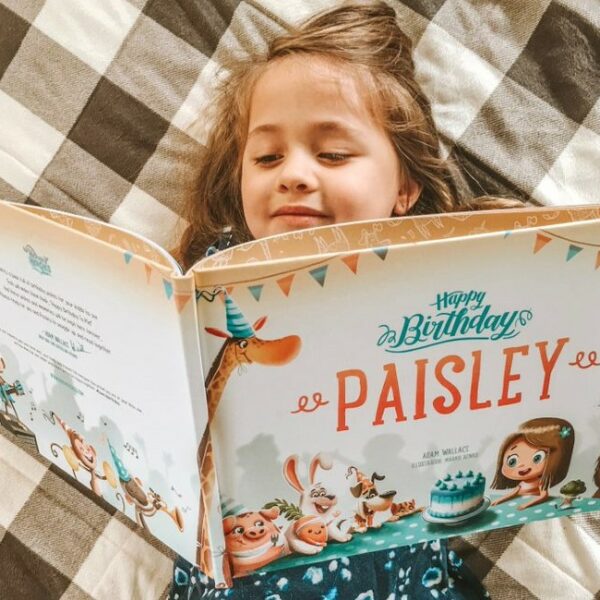 A little girl reading a personalized birthday book from Hooray Heroes.