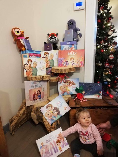 A little girl with a lot of personalized books, looking very proud. 