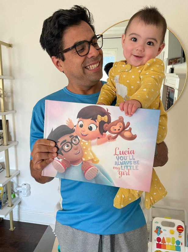 A dad and his daughter proudly showing teir personalized Hooray Heroes book.