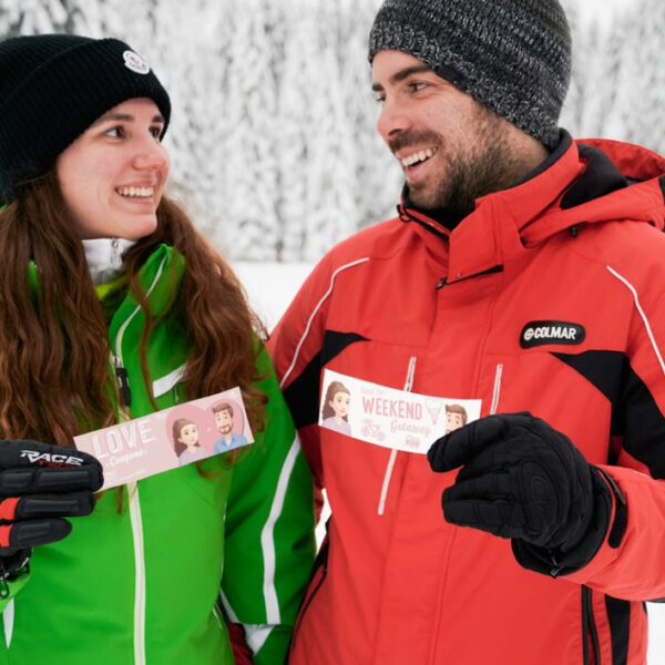 A couple in the snow holding Hooray Heroes personalized love coupons.