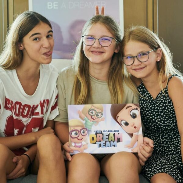 Three sisters with the new personalized books for siblings from Hooray Heroes called The Dream Team.