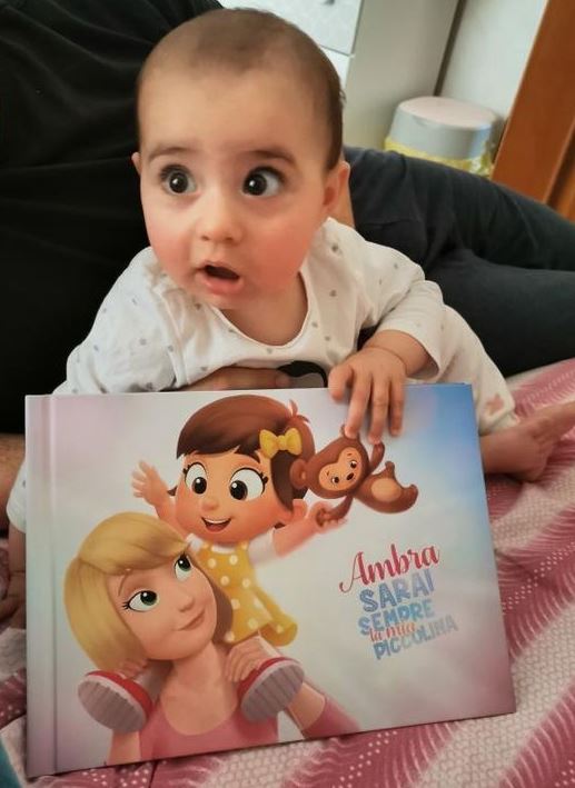A little girl called Ambra holding a personalized book for kids from Hooray Heroes.