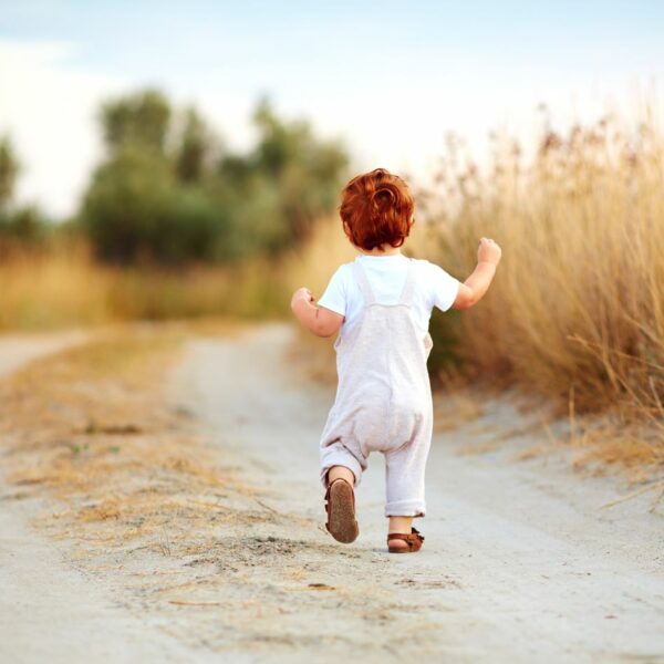 Toddler boy running outside.
