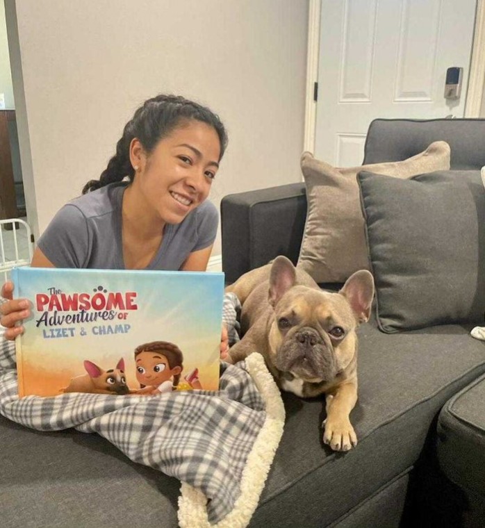 A woman and her Frenchie sitting on a couch with a Hooray Heroes personalized book for pets.