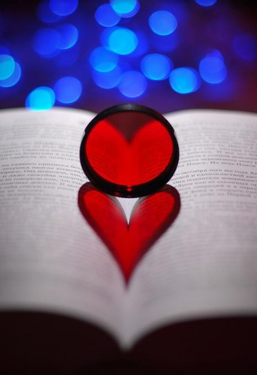 The reflection of a red heart on the pages of an open book. 