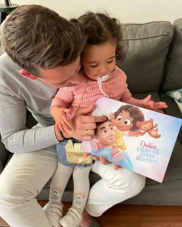 A baby girl named Dalia with her father holding a personalized book by Hooray Heroes.