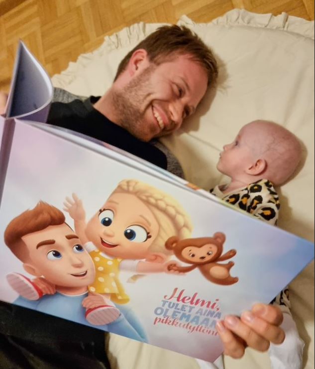 A baby girl named Helmi with her father reading a personalised book by Hooray Heroes.