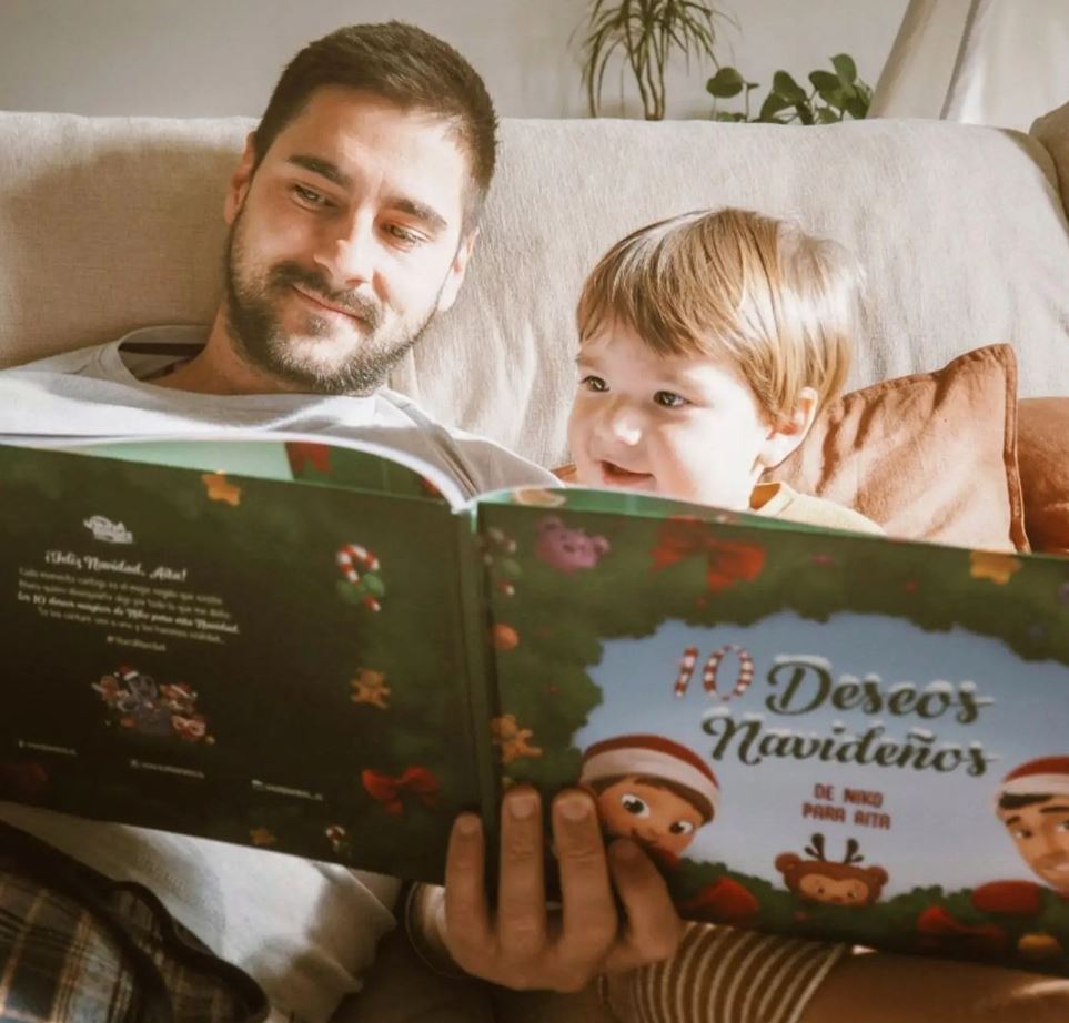 A baby boy named Niko, reading a personalized book from Hooray Heroes with his dad.